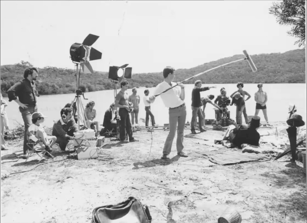 Photo of early film set with sound recorder and boom operator