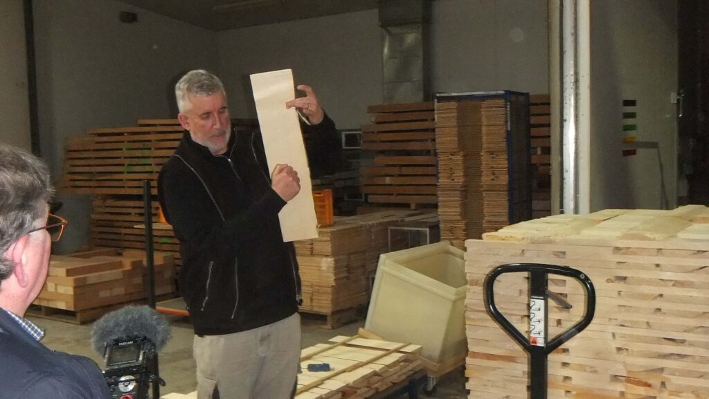 Photo of Patrick Evans demonstrating how to explore the tonal qualities of a timber sample by taps