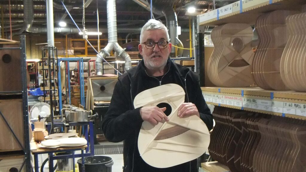 Photo of Patrick explaining the bracing system’s contribution to the guitar’s sound